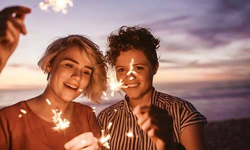 Two young adults playing with sparklers at the beach